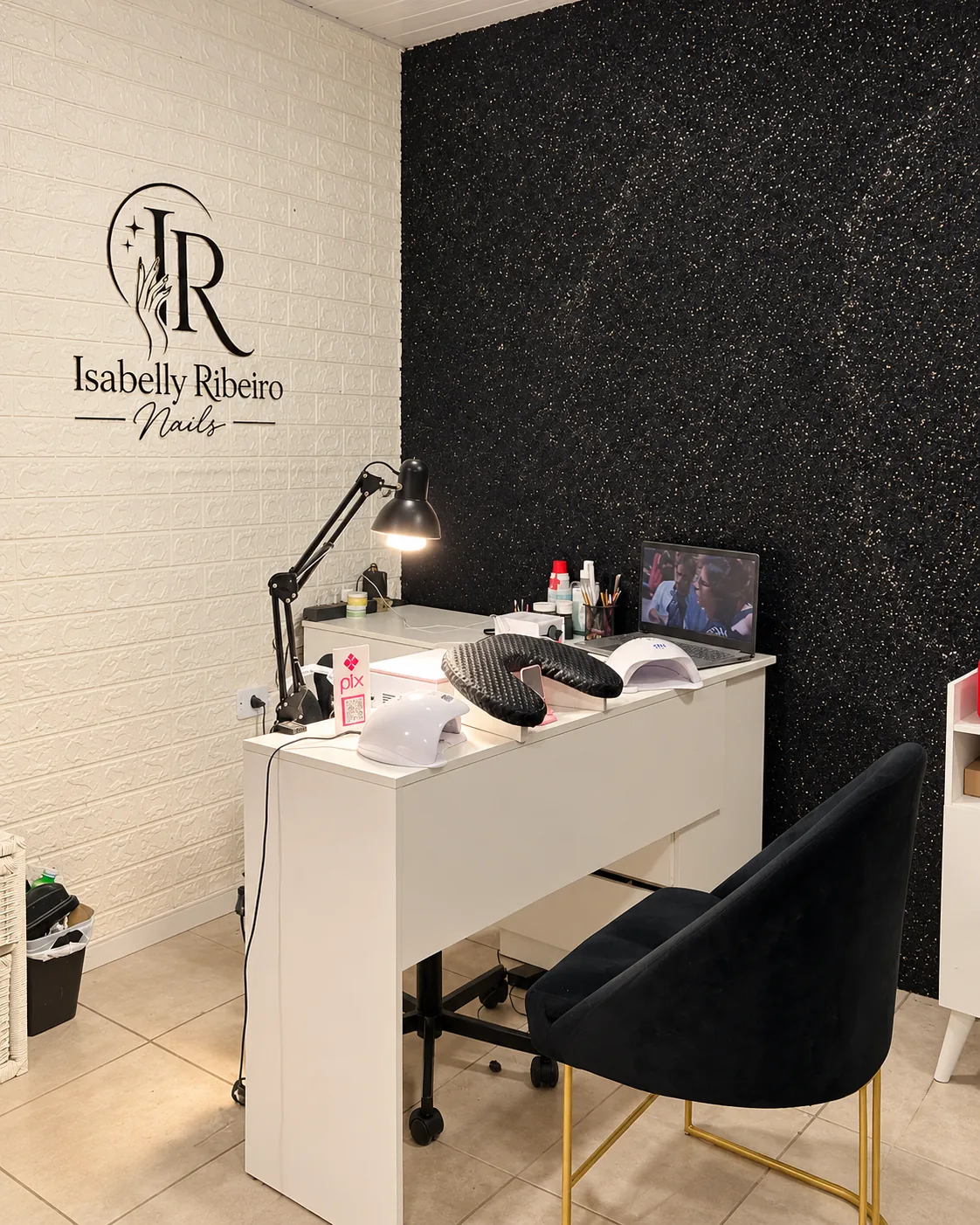 Mesa de atendimento do salão Isabelly Ribeiro Nails, com logo na parede e cadeira para cliente